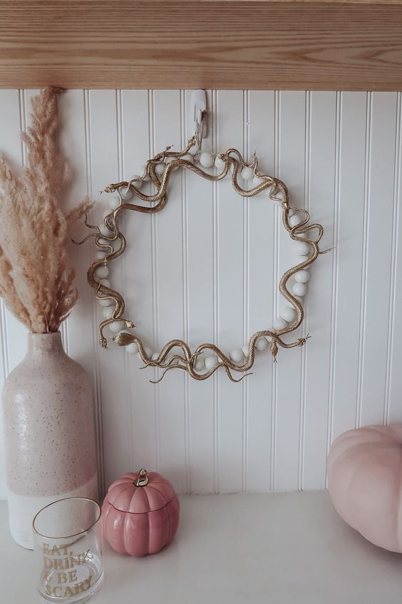 a glam gold snake wreath with large pearls is a nice and chic idea for a glam Halloween space