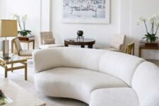 11 a neutral living room with a white curved sofa, a coffee table, side tables, chairs and an artwork, some potted blooms