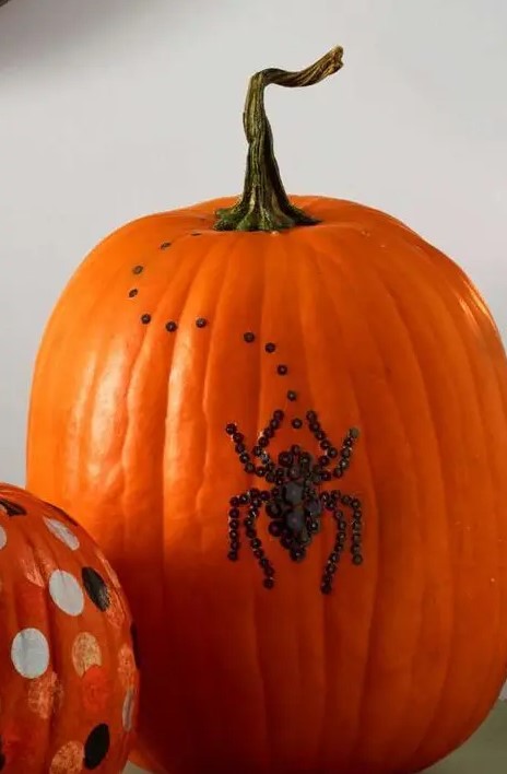 a natural orange pumpkin decorated with black sequins showing a spider is a beautiful and very cool idea that you can realize last minute