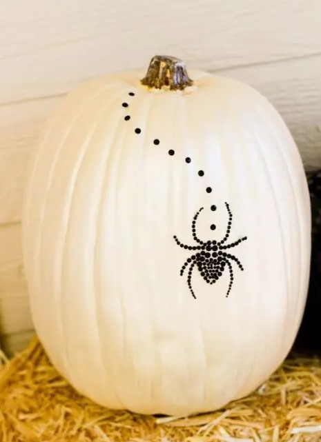 a white pumpkin with black studs and a black spider of them is a creative and cool non-carving pumpkin idea