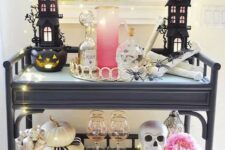 15 a glam Halloween bar cart with scary houses, skulls, a pink bloom, neutral pumpkins, lights and a black letter banner