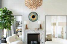 17 a sophisticated living room with a marble clad fireplace, a curved creamy sofa and matching chairs, black coffee tables, a quirky chandelier