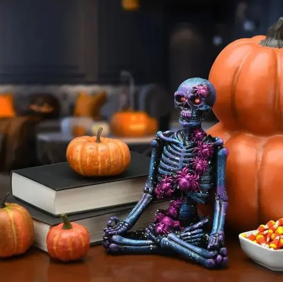 a black meditating skeleton covered with purple spiders is a cool and bold idea to decorate your space for Halloween