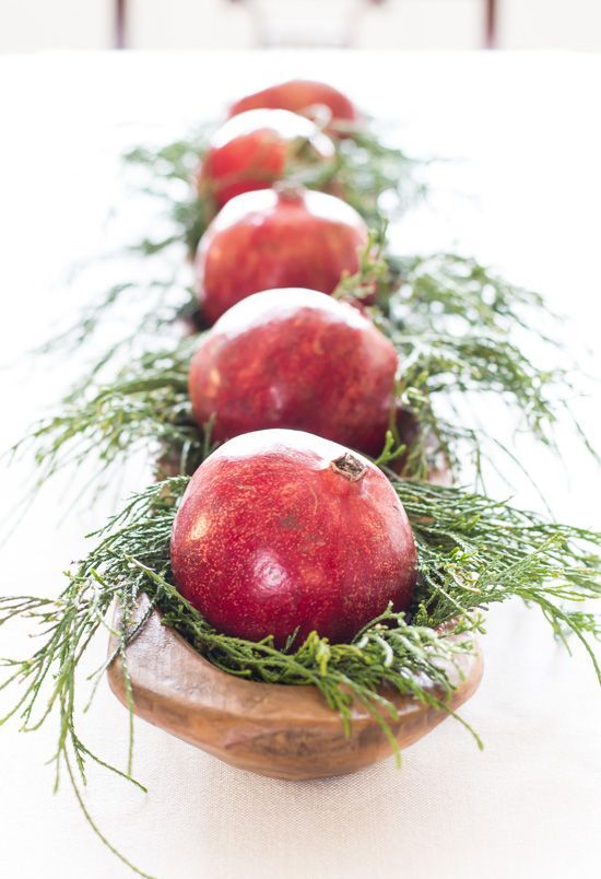 a long wooden bowl with evergreens and pomegranates is a cool idea for fall, winter and Christmas
