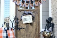 19 a Halloween porch with white and orange pumpkins, candle lanterns, buntings, a black skeleton and black branches plus a twig wreath