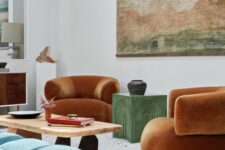 19 a colorful living room with rust-colored curved chairs, a green coffee table, a coffee table, a blue ottoman, an artwork and a sideboard