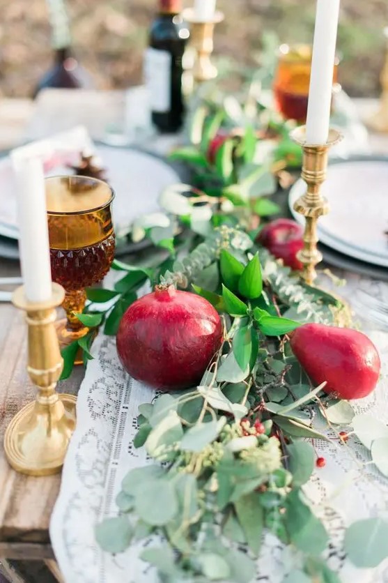 a lush and bold table runner of greenery, pears and pomegranates, berries and thin and tall candles is amazing for the fall