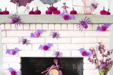 20 a bright and chic Halloween mantel with fuchsia velvet pumpkins, purple bats and spiders, pink skull hands and pastel bats
