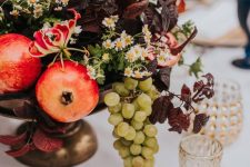 20 a lush centerpiece of chamomiles, dark foliage, pomegranates, bold blooms and grapes is great for your tablescape