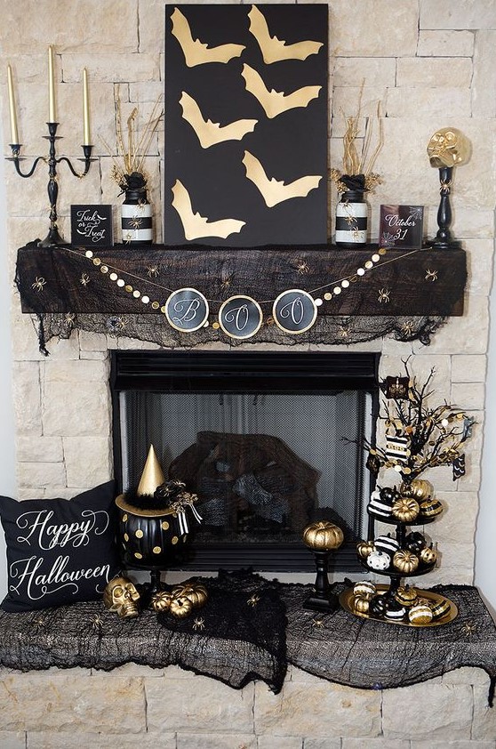 a sophisticated Halloween mantel with gold bats, gold skulls, pumpkins and candles, branches, a stand with lots of pumpkins