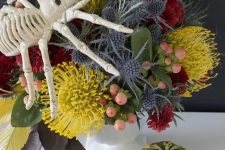 21 a bright floral arrangement with mustard, red blooms, berries and thistles plus a large spider on top