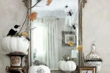22 vintage Halloween decor with a large mirror in an ornated frame, white pumpkins with patterns and blackbirds plus spiders and fall leaves