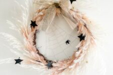 24 a beautiful celestial Halloween wreath with pampas grass, black stars, a spiderweb, a glitter bow is amazingg