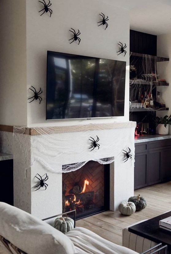 a fireplace covered with faux spiderweb and black spiders, a couple of heirloom pumpkins is a gorgeous idea for Halloween