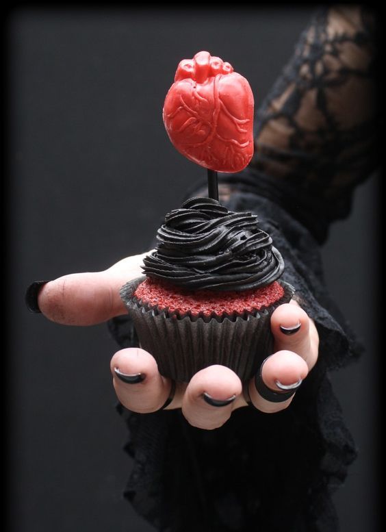 a red velvet cupcake topped with black chocolate frosting and a red heart looks absolutely jaw-dropping