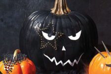 24 a stylish black and white Halloween pumpkin with a face and a star-shaped tattoo done with decorative pins