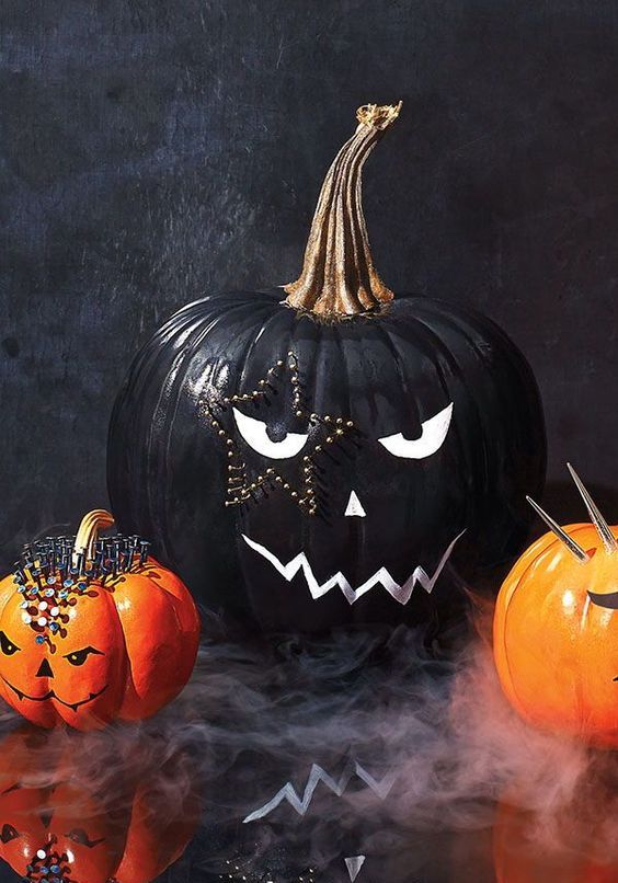 A stylish black and white Halloween pumpkin with a face and a star shaped tattoo done with decorative pins