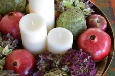 25 a rustic centerpiece of green and purple hydrangeas, apples, pomegranates, artichokes and pillar candles