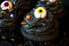 25 black chocolate cupcakes with colorful confetti and eyeballs on top are amazing for treating your guests at a Halloween party