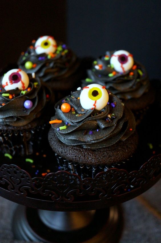 black chocolate cupcakes with colorful confetti and eyeballs on top are amazing for treating your guests at a Halloween party