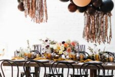 26 a celestial Halloween party tablescape with bold blooms, a balloon overhead installation, yellow napkins and black chairs