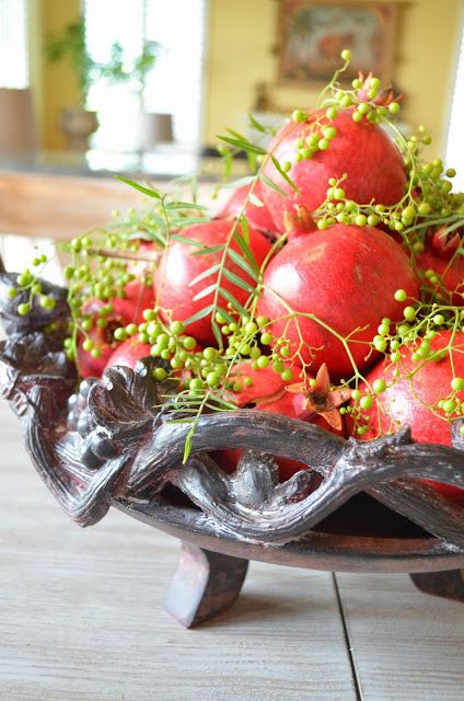 a simple and catchy centerpiece of pomegranates and greenery plus berries is a catchy idea for fall and Thanksgiving