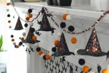 29 a cool Halloween garland of felt balls in white, orange and black and shiny witches’ hats is a great idea to rock