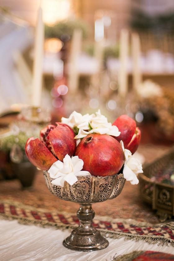 a simple and chic centerpiece of a vintage bowl, white blooms and pomegranates is a catchy idea for fall and winter