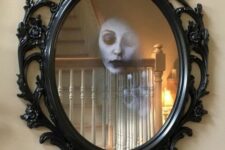 29 dramatic Halloween mirror decor with a ghost face inside it is a cool decoration for any Halloween space