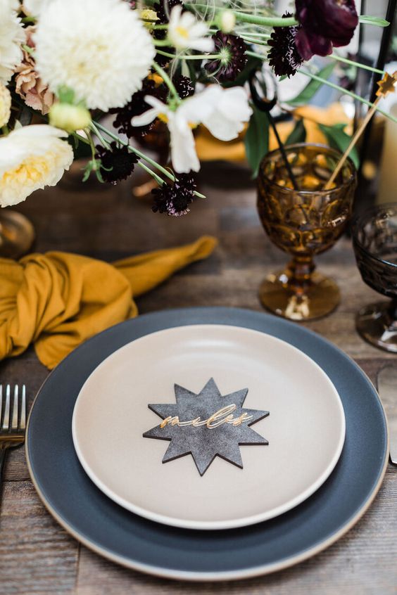 A chic celestial Halloween table setting with a star shaped card and dark glasses, bold blooms is amazing