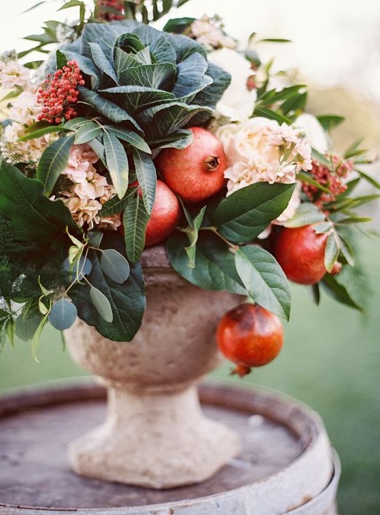 a super lush fall centerpiece of arrangement of white and blush blooms, greenery, cabbage and pomegranates