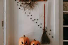 31 style your entryway with jack-o-lanterns, spiders climbing up the wall, a broom and a twig wreath for Halloween