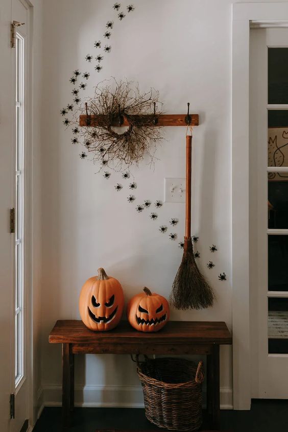 Style your entryway with jack o lanterns, spiders climbing up the wall, a broom and a twig wreath for Halloween