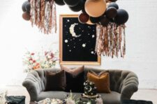 32 a gorgeous celestial Halloween lounge with dark seating furniture, a balloon installation, a moon wall art and some blooms