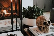32 stylish Halloween decor with black candles in candleholders, black spiders, a beautiful ornated skull abd some spiders on the fireplace