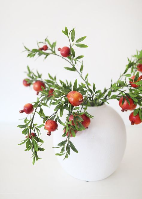 A very easy fall centerpiece of a large white vase and branches with pomegranates is a cool last minute idea