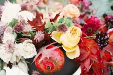 35 an adorable fall centerpiece of a grey vase, yellow, pink and deep red blooms, fall leaves and pomegranates that help to embrace the fall