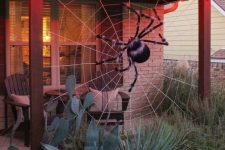 36 a back porch decorated with a giant spiderweb and a fluffy spider is a cool idea to style your outdoor space for Halloween without much effort