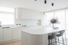 36 a minimalist white kitchen with curved cabinets, a white marble backsplash, a curved ribbed kitchen island and tall grey stools