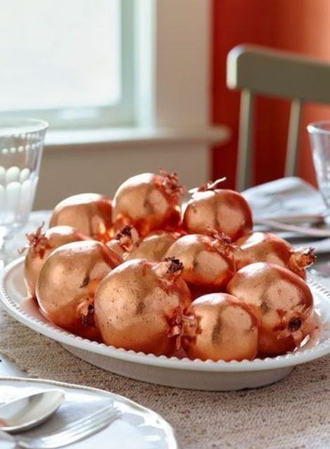 make a simple fall centerpiece of faux pomegranates and copper spray paint, that's an easy and glam solution