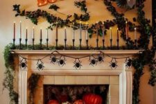 38 a jaw-dropping Halloween mantel with a moss garland and lots of candles, greenery on the wall, lots of colorful pumpkins and jack-o-lanterns in the fireplace