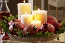 38 make a stunning fall centerpiece with pillar candles surrounded with pomegranates and greenery