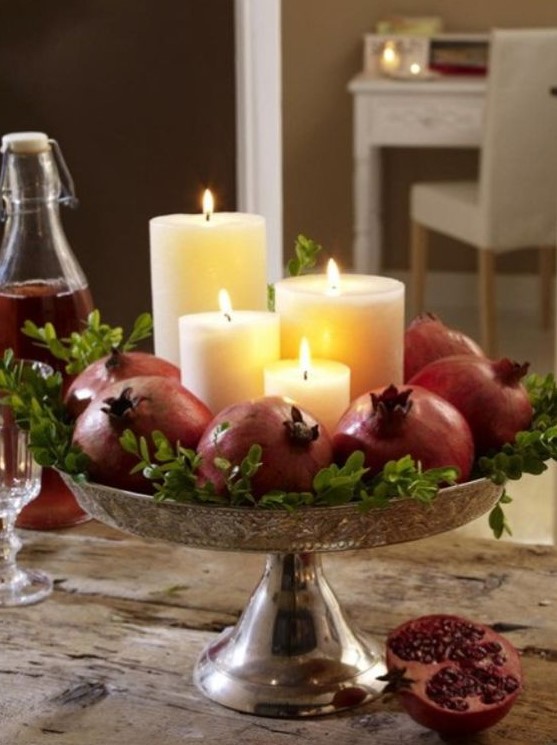 make a stunning fall centerpiece with pillar candles surrounded with pomegranates and greenery