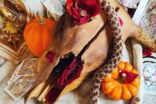 39 an animal skull decorated with blooms and a resin snake plus some pumpkins around for bold and chic Halloween decor