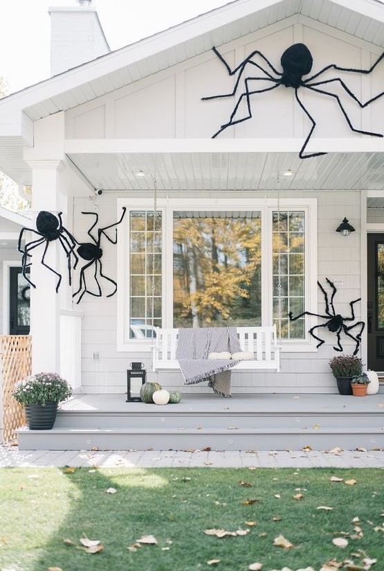 a house styled with giant black spiders looks scary and Halloween-like but still remains a farmhouse-style dwelling with an organic and natural feel