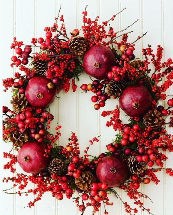 a bold abd catchy wreath for fall or Christmas made of pomegranates, berries, mini apples and pinecones