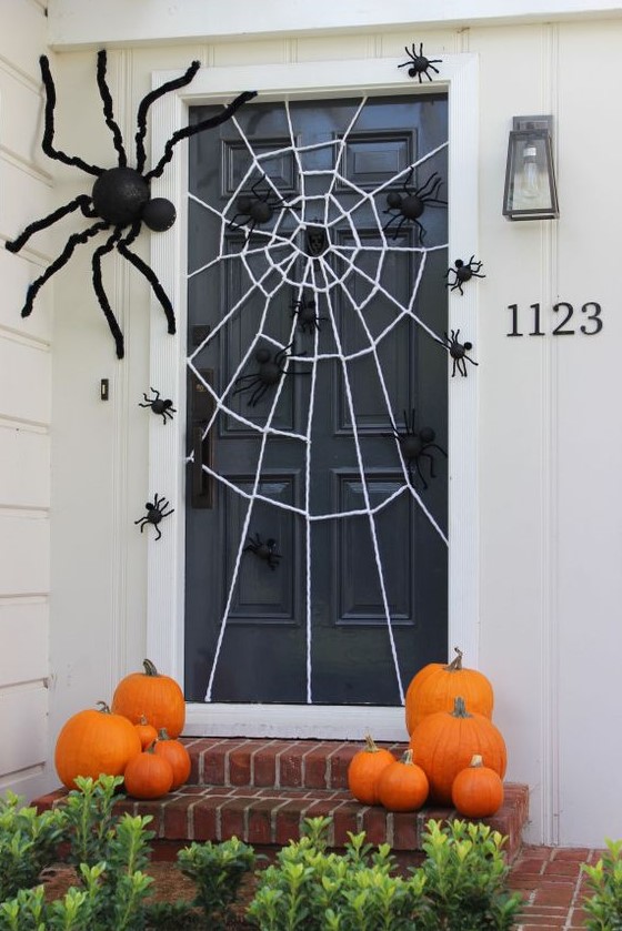 a spiderweb and lots of black spiders make the front porch Halloween-ready and stylish