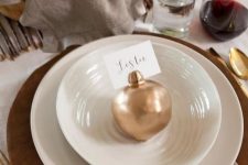 43 a chic fall place setting with a wooden placemat, white plates, a neutral napkin and a gilded pomegranate