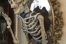 44 a scary glam Halloween decoration of a vintage mirror with a glam embellished half skeleton attached is elegant