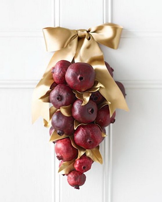 an outdoor fall decoration of pomegranates, gilded leaves and an oversized gold bow is a cool idea for outdoors